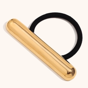 Détail d'une barrette cylindrique minimaliste plaquée or 18K sur un élastique noir