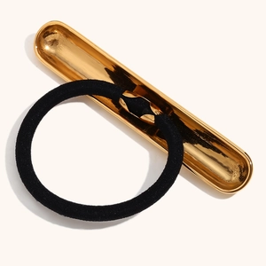 Détail d'élastique à cheveux noir avec boucle en métal doré 18K sur un plateau doré