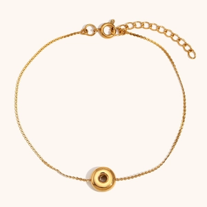 Macro view of 18K gold plated chain bracelet with doughnut ring charm and lobster clasp