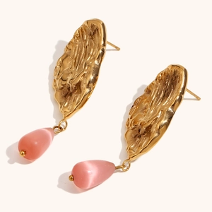 Detail of gold hammered metal stud earrings with pink teardrop semi-transparent stones