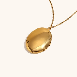 Detailed close-up of a polished gold oval locket pendant with a high-shine mirror finish