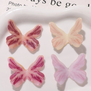 Macro shot of 4 gradient resin butterfly charms with glitter finish for DIY crafts