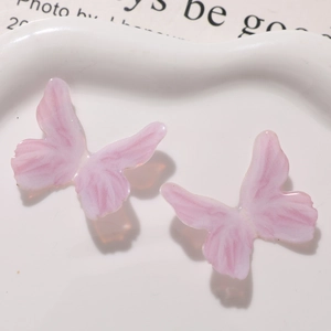 Detailed close-up of pink glitter resin butterfly charms on a white ceramic plate