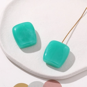Detail view of mint green resin square earrings with a subtle marble texture and gold studs