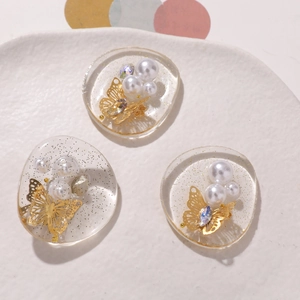 Macro view of transparent resin charms with gold butterfly and pearl inlay decorations