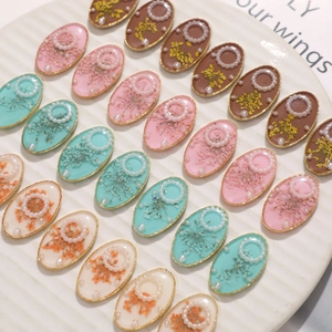Oval resin charms with dried flowers and pearls in pink, blue, and white for DIY crafts