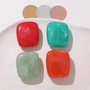 Macro view of marbled resin square beads for DIY jewelry making on white ceramic plate