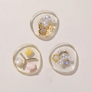 Macro shot of resin DIY craft accessories featuring pearls, gold butterflies, and crystals