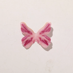Detail view of pink resin butterfly accessory with glitter finish and feather texture