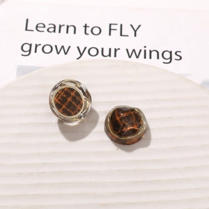 Macro detail of round tortoiseshell resin earrings with fine gold metal borders