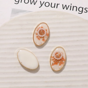 Detailed oval resin charms with orange dried flowers and pearls in gold alloy frames