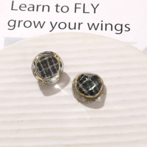Close-up of vintage resin charms with black plaid fabric inlay and gold metal edges