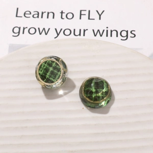 Detailed close-up of vintage resin earrings with green plaid pattern and gold frame