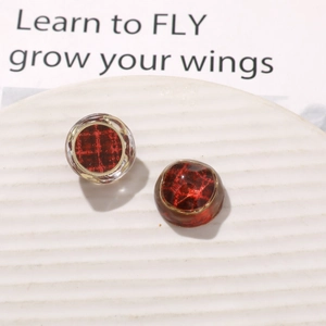 Detailed macro view of vintage red plaid resin charms with elegant gold metal frames