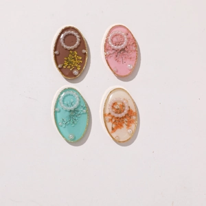 Detailed close-up of oval resin cabochons featuring real dried flowers and small pearls
