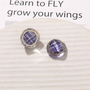 Detail of purple plaid resin earrings with gold metal edges on a ceramic display