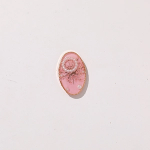 Detailed macro view of oval resin pendant with pink dried flowers and white pearls