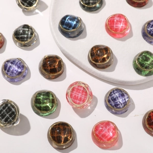 Detail of dome resin buttons with plaid fabric inlay and elegant gold metal frame