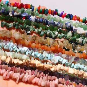 Hand holding colorful natural semi-precious irregular stone beads for DIY jewelry making