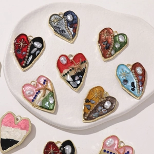Dettaglio di ciondoli a cuore in lega con resina, perle finte e pietre colorate tritate