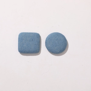 Close-up of square and round light blue denim fabric covered buttons for DIY sewing