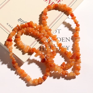 Polished natural orange gemstone chips layered on a vintage book for DIY jewelry making