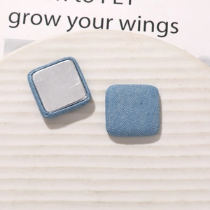 Macro detail of light blue denim fabric square buttons with flat silver metal backings