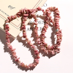 Close-up of natural pink irregular stone chips necklace on a minimalist book background
