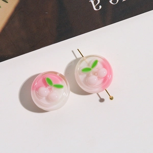 Close-up of pink resin cherry beads with a golden pin showing the DIY assembly detail