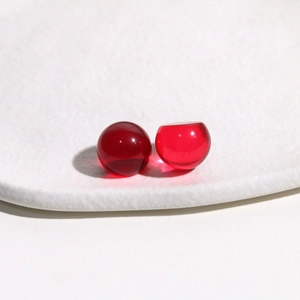 Detailed macro view of two translucent red 14mm round resin cabochons on white textured background