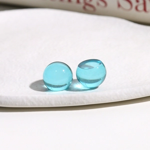 Close-up of two light blue transparent resin round cabochons on a white ceramic plate