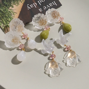 Detailed shot of matte resin floral and bird earrings with elegant bead accents