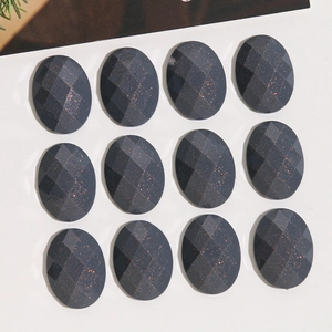 Macro view of twelve oval glitter resin cabochons with faceted dark grey starburst finish