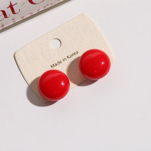 Detail of red round resin stud earrings with glossy finish on display card