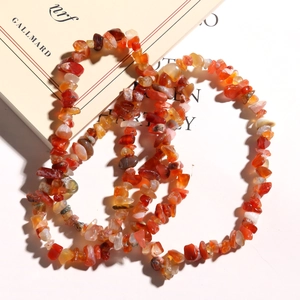 Detail of red carnelian irregular natural stone chips wrapped on a minimalist book background