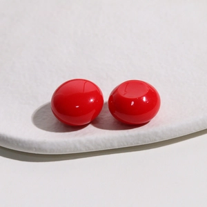 Close-up of polished 18mm red resin dome cabochon on a white tray for jewelry making