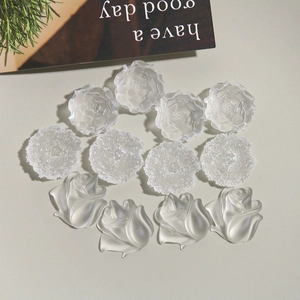Macro detail of matte white resin tulip and rose flower charms for DIY jewelry making