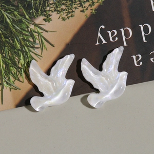 Détail de breloques hirondelles en résine nacrée blanche pour bijoux et accessoires