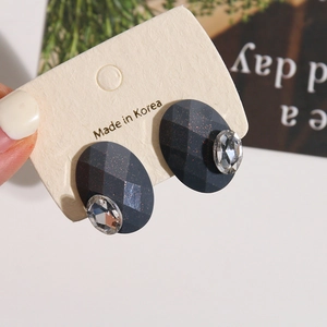 Detailed view of dark grey oval resin earrings with gold glitter and crystal accents
