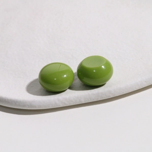 Close-up of shiny grass green round resin beads on a white textured display tray