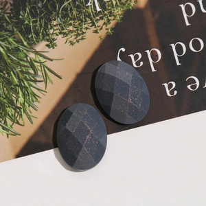 Close-up of oval faceted dark gray glitter resin stones on a lifestyle background
