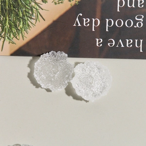 Macro detail of white translucent resin floral charms with frosted embossed texture
