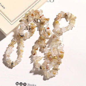 Close-up of irregular natural rutilated quartz stone beads with golden needle inclusions