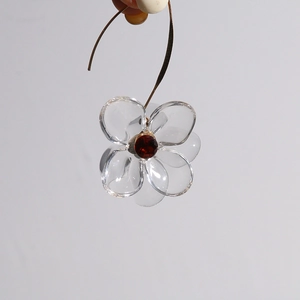 Detailed view of a transparent acrylic flower earring with a red gem and gold hook