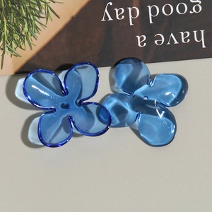 Macro detail of blue translucent acrylic four-petal flower charms for DIY jewelry making