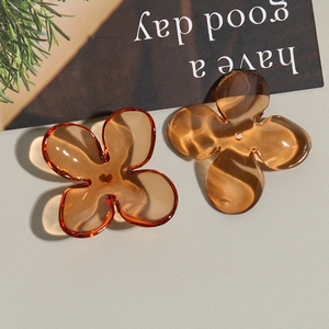 Detailed macro view of two amber acrylic four-petal flower charms for DIY jewelry making