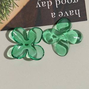 Close-up of translucent green acrylic four-petal flower beads for DIY jewelry making