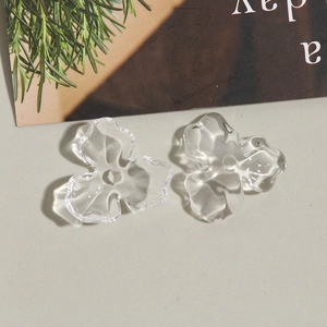 Gros plan de breloques tulipes transparentes pour bijoux DIY dans un décor épuré