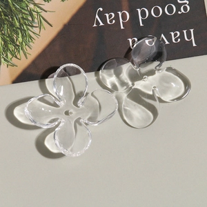 Macro detail of clear acrylic four-petal flower charms with center hole for DIY earrings