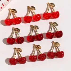 Macro shot of 3D glitter cherry charms with gold leaves for DIY jewelry making